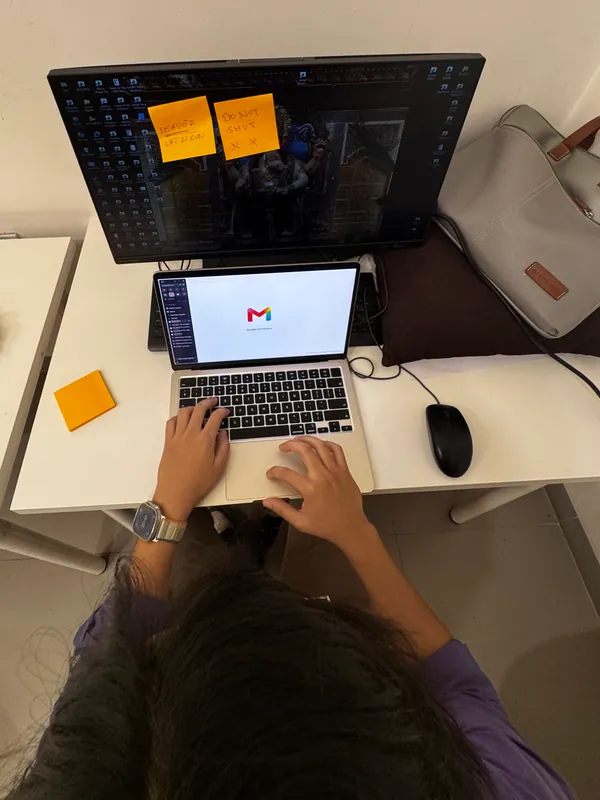 An overhead view of a laptop, monitor and hands at the keyboard
