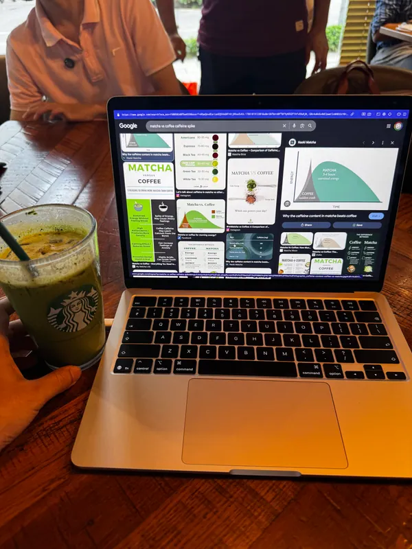 A laptop and an iced matcha on a cafe table